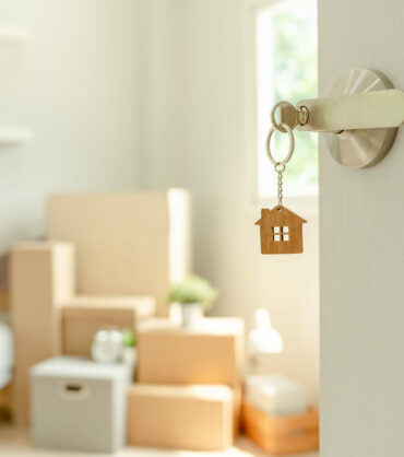 Moving house, relocation. The key was inserted into the door of the new house, inside the room was a cardboard box containing personal belongings and furniture. move in the apartment or condominium