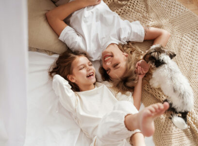 Cute dog is with them. Mother with daughter are at home together.