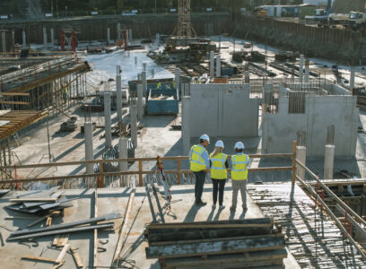 Aerial Shot of a New Constructions Development Site with Diverse team of Engineers and Architects Discussing Real Estate Projects. Heavy Machinery and Construction Workers are Working in the Area.
