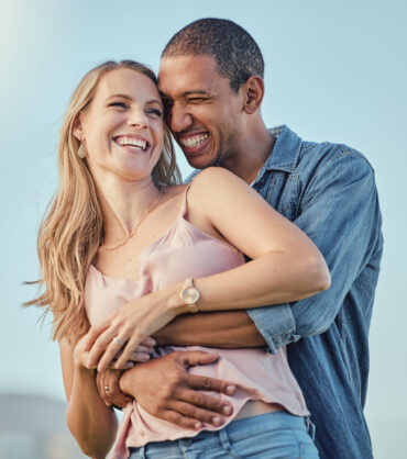 Love, diversity and couple hug on vacation, holiday or summer trip. Romantic, relax smile and happy man and woman hugging, embrace or cuddle, having fun and enjoying quality time together outdoors